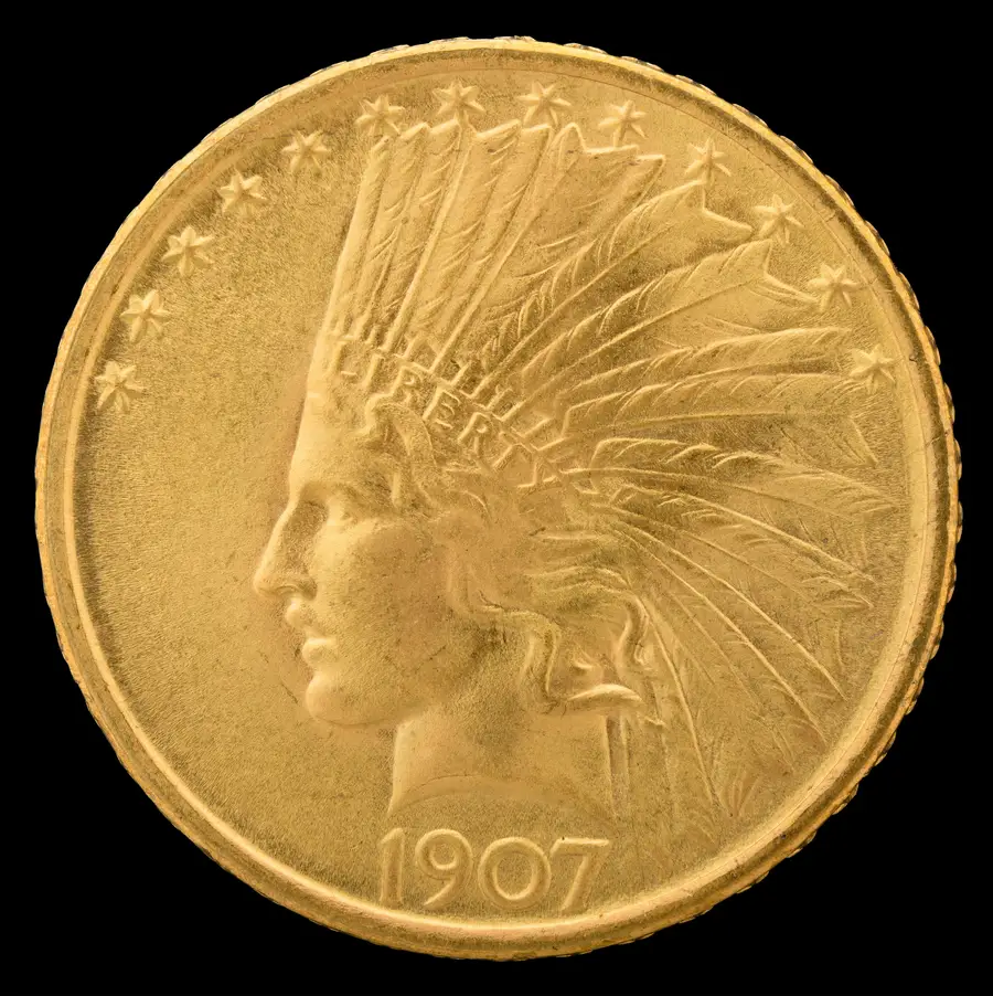 インディアンヘッド10ドル金貨（1907年）の表面。羽根飾りの頭飾りを着けた自由の女神の横顔と LIBERTY の銘